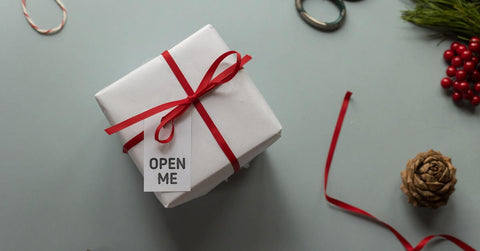 A white box with a red ribbon and a card that says “Open me.”