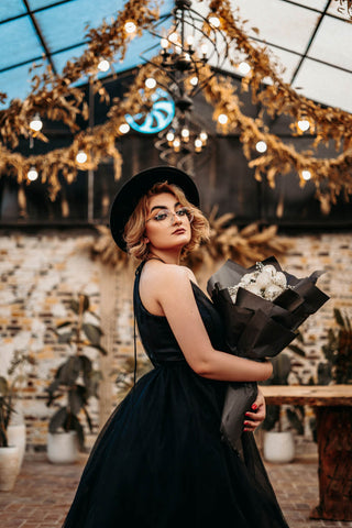 Woman posing with a black dress and holding flowers