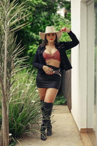 Photo of a woman wearing a leather mini skirt, bra top, knee boots and cowboy hat