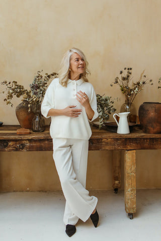 Elderly woman posing in white palazzo pants and a white blouse