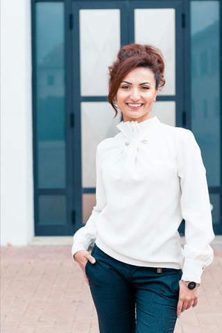 Woman posing with an elegant white blouse and suit pants