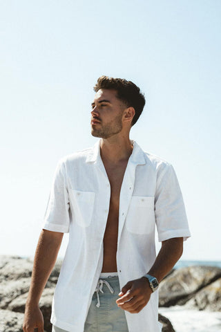 Man posing with an unbuttoned white linen shirt