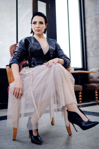 Woman posing sitting with a tule skirt and a black leather jacket