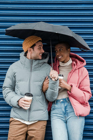 A couple with umbrella wearing winter jackets