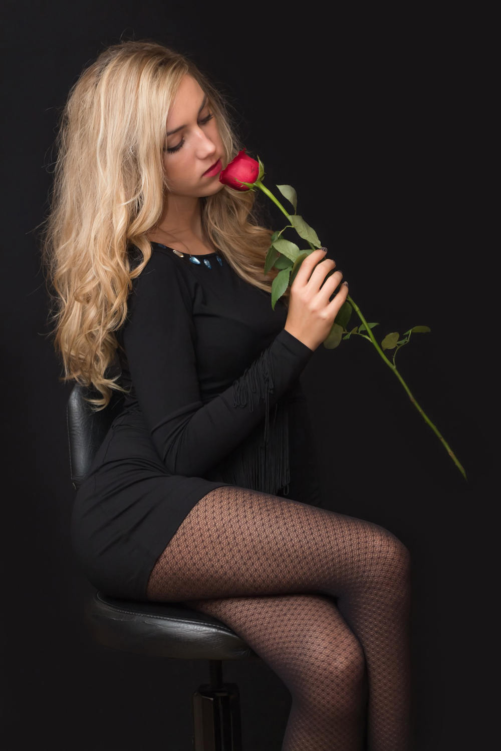 Girl holding a red rose wearing a black dress