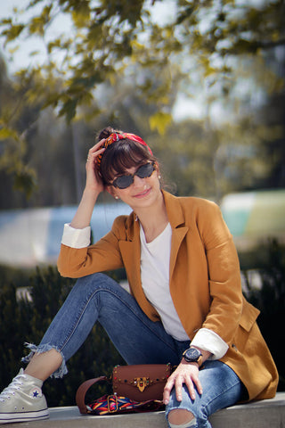 Glückliche Frau posiert in Jeans, Khaki-Blazer und Sonnenbrille