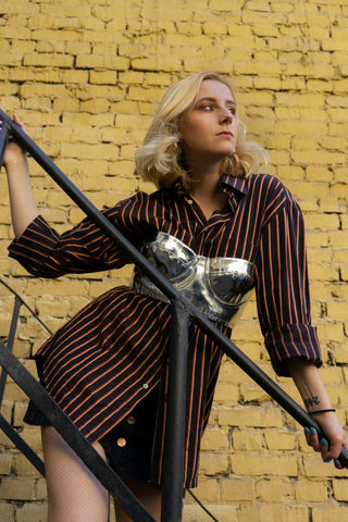 Woman posing for a photo wearing a silver corset top over a dark shirt