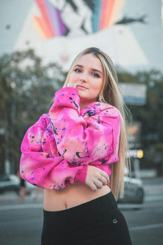 Girl posing with bright-colored cropped hoodie and black leggings