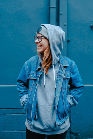 Girl posing in a grey hoodie under a blue denim jacket