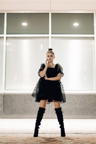 Girl posing with high-knee boots and a black dress