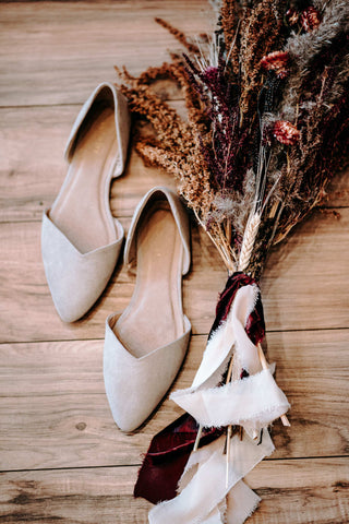 white pointed-toe ballerina flats with a bunch of dry flowers