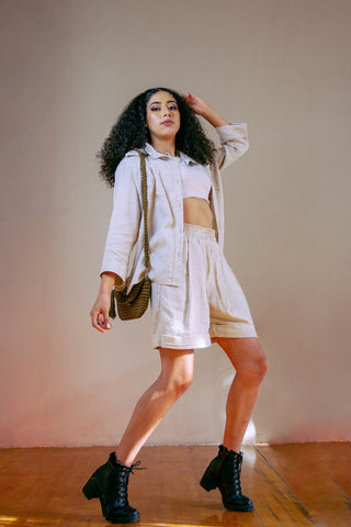 Woman posing in linen tailored shorts and jacket, and leather ankle boots