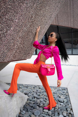 Woman posing with orange bell-bottoms and a fuchsia shirt