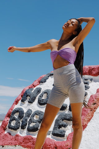 Woman posing in grey bike shorts and a purple top