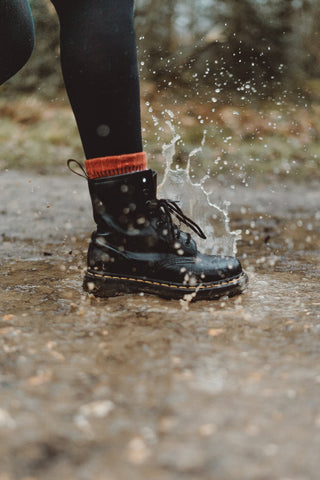 Une photo d'une botte à cordes noires marchant sous la pluie