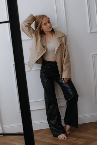 Woman posing in black faux leather pants and cream leather jacket