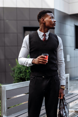 Man posing in an elegant outfit with a vest and a classic button-up