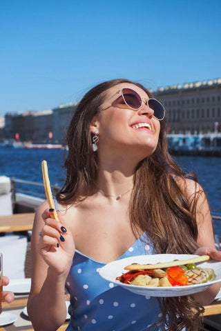 Femme heureuse sur un bateau, profitant de la nourriture et du soleil