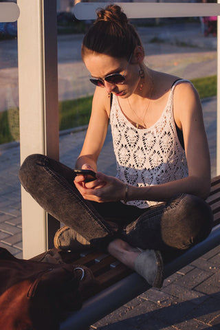 Young girl looking at her phone wearing a relaxed outfit and hemp shoes