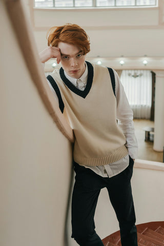 Young man posing with a vest over a white shirt and black jeans
