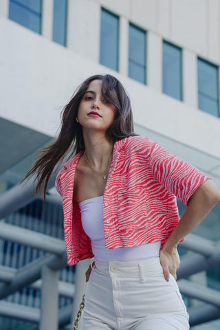 A woman posing in white jeans and a red cropped jacket