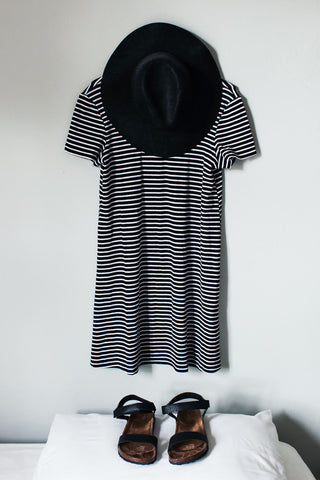 Photo of black wide-brimmed hat, a stripped flannel dress and black sandals