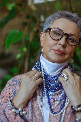Mature woman wearing glasses and jewelry of blue and white pearls