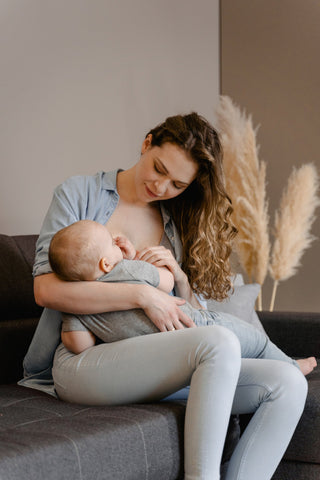Woman holding her child breastfeeding in a casual outfit