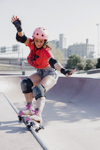 Woman performing tricks on roller skates wearing protective gear and a helmet