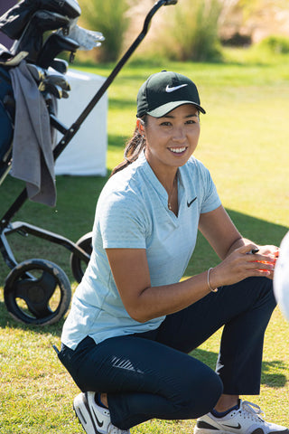 Woman smiling on a golf course wearing golf attire