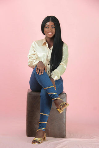 Black woman posing sitting with a satin shirt and jeans