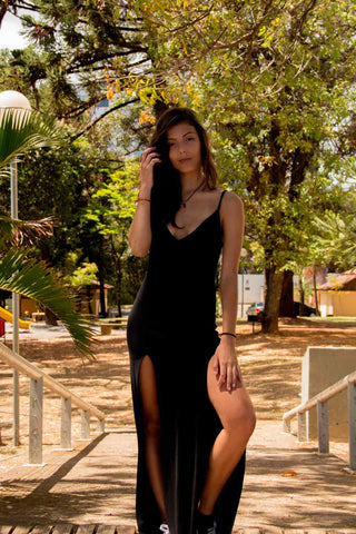 Woman posing in a black slip dress with two lateral slits