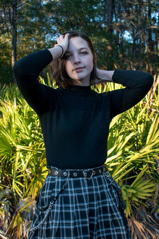 Close photo of a girl wearing a tartan skirt and a black blouse