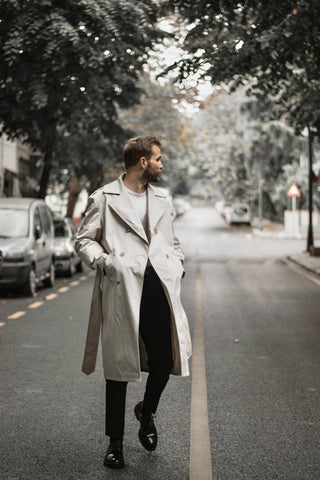 A man on the street wearing a trench coat over a casual outfit