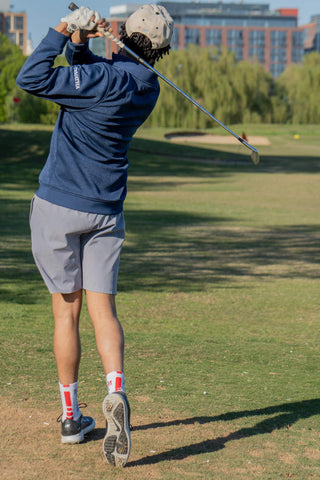 A photo of the back of a man playing golf in golf apparel and shoes