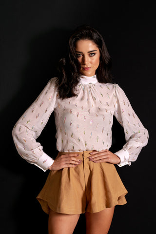 Woman posing in a white blouse and brown skirt on black background