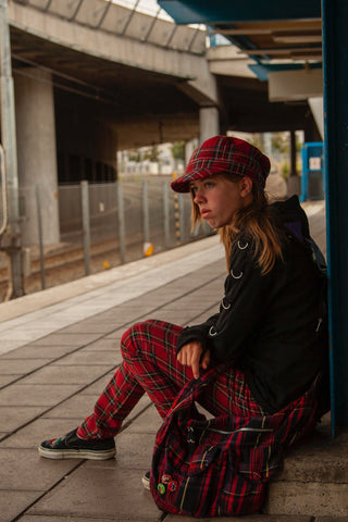 Girl sitting at a train station and wearing plaid outfit