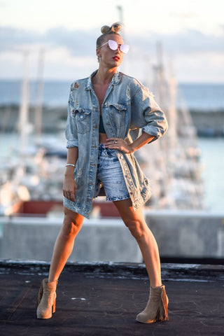 Woman posing with an oversized denim jacket and distressed denim shorts