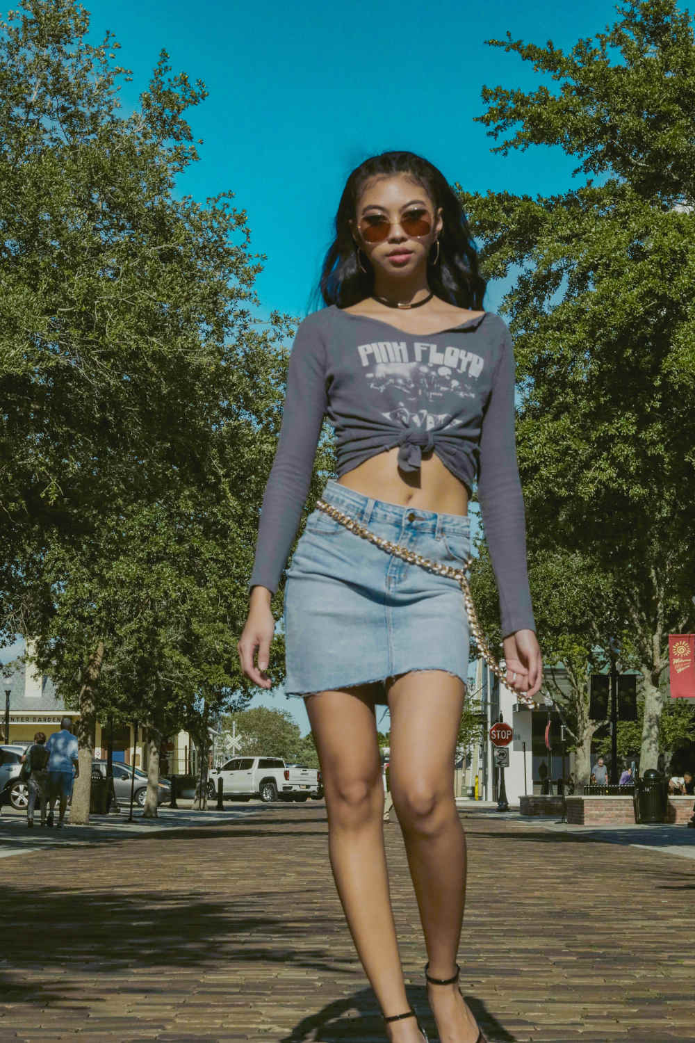 Asian woman posing with a graphic top and a denim skirt