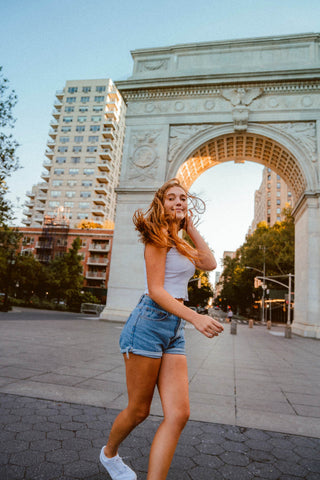 Mädchen läuft in Jeansshorts und weißem Top durch die Stadt