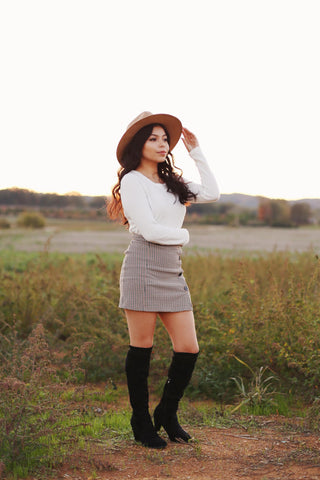 Woman posing in knee boots, mini skirt and white long sleeve top