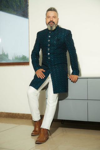 Man posing in blue kurta, white pants, and ankle boots