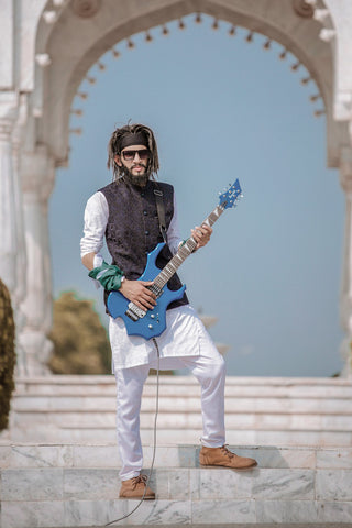 Man playing guitar in kurta, white jeans and ankle boots