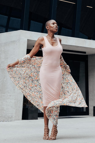 Black woman posing with a baby pink bodycon dress and a colorful shawl