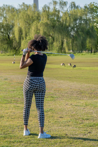 Woman playing golf wearing patterned capri pants and a top