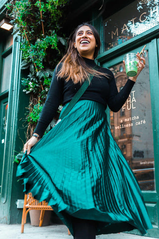 Happy woman in green pleated skirt and black turtleneck