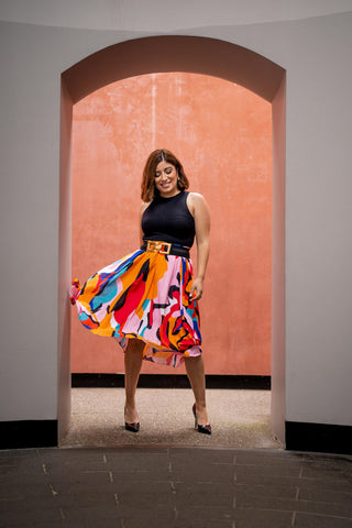 Woman posing with a colorful pleated skirt and a black sleeveless top