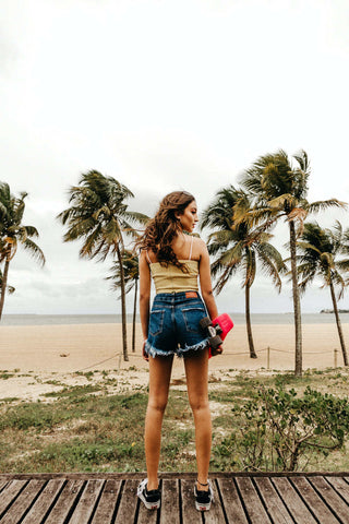 Girl posing in denim shorts and a camisole top and black vans