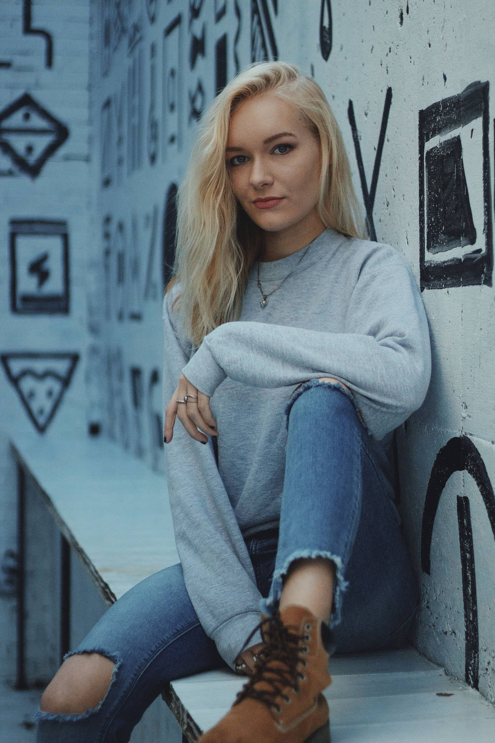 Young woman posing with a grey sweater and ripped jeans