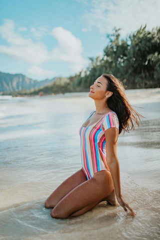 Frau posiert mit buntem Badeanzug am Meer